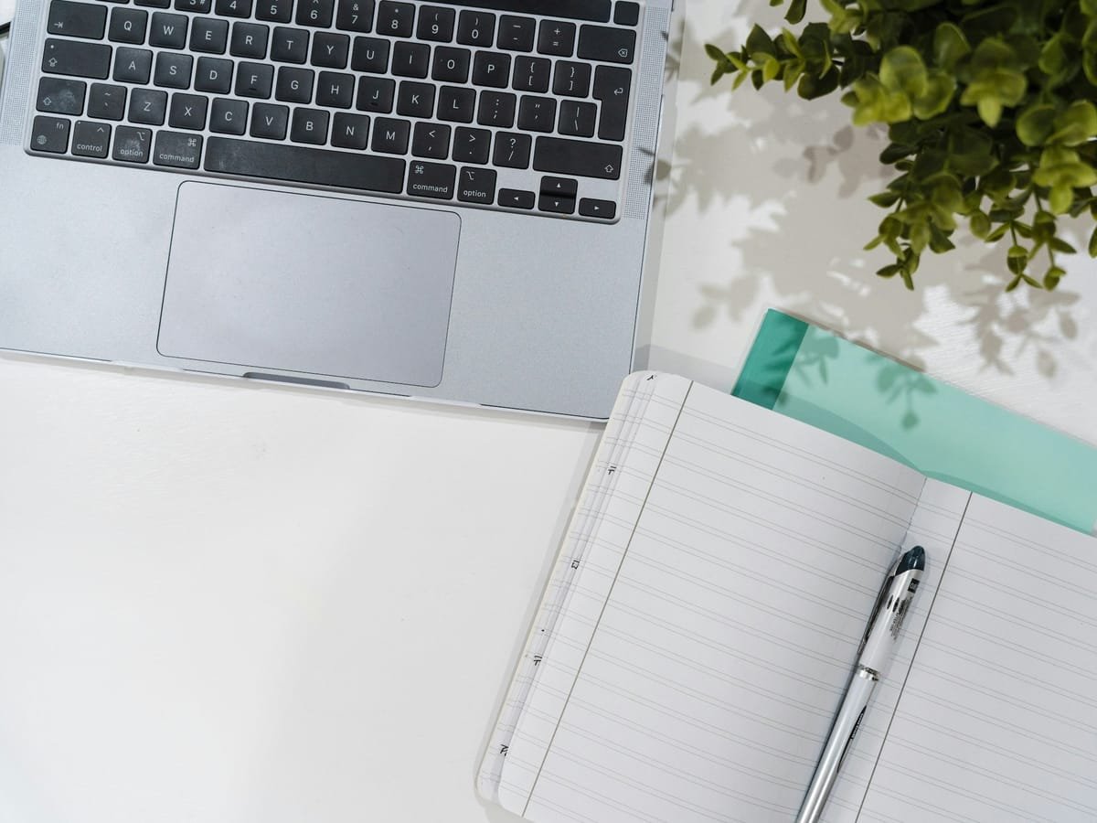 Organized desk with a laptop, an open notebook and a folder