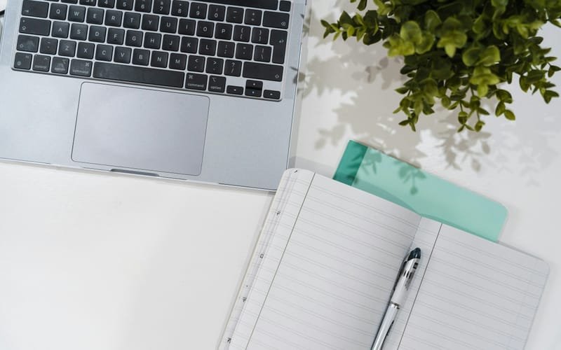 Organized desk with a laptop, an open notebook and a folder